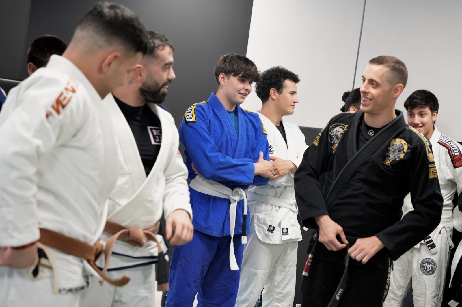 Raúl, instructor de NEKO, charlando y sonriendo con un grupo de alumnos con kimono antes de entrenar Jiu-Jitsu en Madrid